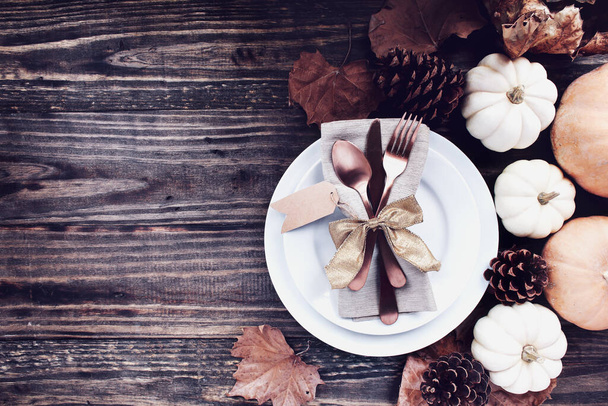 A holiday place setting with plate, napkin, on a Thanksgiving Day decorated table shot from flat lay or top view position. Silverware tied with gold ribbon bow.  - Foto, Bild