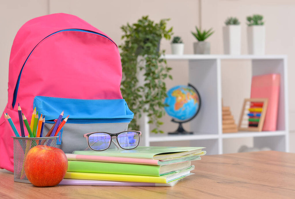 Backpack,apple, school supplies on the background of the school classroom .Back to school and kindergarten . The beginning of the school season. - Foto, immagini