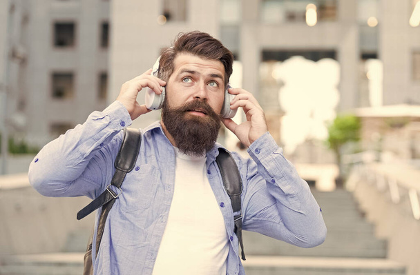 We have our ears in the streets. Bearded man wear ear phones outdoors. Hipster listen to music in headphones. Comfortable ear pads. Hearing protection. Modern life. Ear knowledge for your soul - Photo, Image