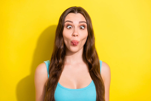 Photo of funny brunette hairdo young lady show grimace wear teal top isolated on vivid yellow color background - Fotó, kép