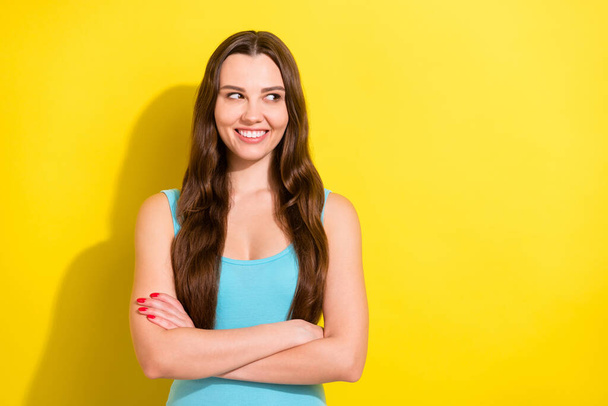 Photo of sweet brunette hairdo young lady crossed arms look empty space wear teal top isolated on vivid yellow color background - Fotoğraf, Görsel