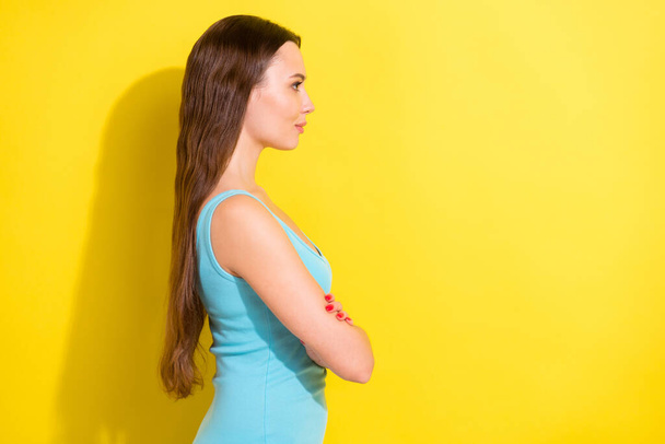 Side profile photo portrait girl with long hair wearing blue singlet smiling folded hands looking copyspace isolated vibrant yellow color background - Foto, imagen