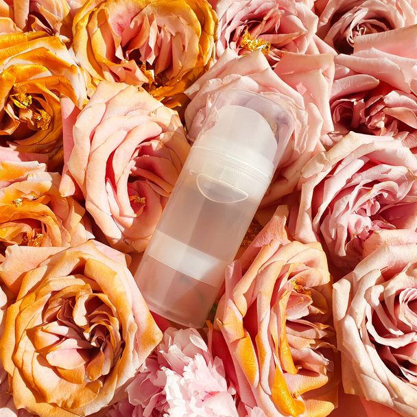 Unbranded transparante fles Intieme glijmiddel gel en roze gouden rozen. Intieme massage en comfortabele sex consept. Cosmetische fles. Lifestyle, flatlay, bovenaanzicht, sjabloon. - Foto, afbeelding