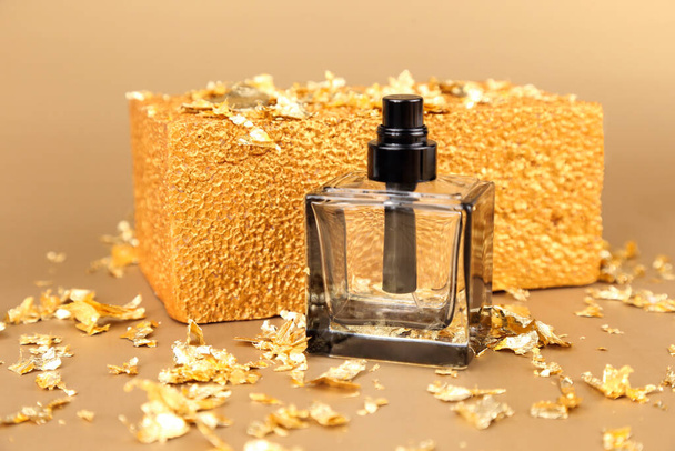 Unbranded black square perfume spray bottle, pieces of gold paper and golden rectangular shape on golden background. Front view, mockup, template. - Photo, Image