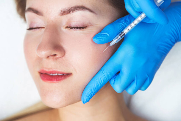 Procédure d'injections faciales rajeunissantes pour resserrer et lisser les rides sur la peau du visage - Photo, image