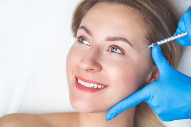 Procédure d'injections faciales rajeunissantes pour resserrer et lisser les rides sur la peau du visage - Photo, image