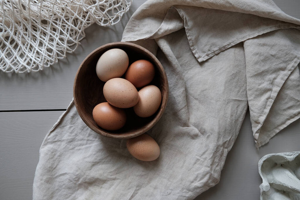 A bowl of fresh brown eggs on a piece of cloth on the kitchen table - Фото, зображення
