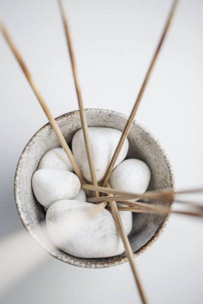A vertical shot of white rocks and straw sticks in a pot - Фото, изображение