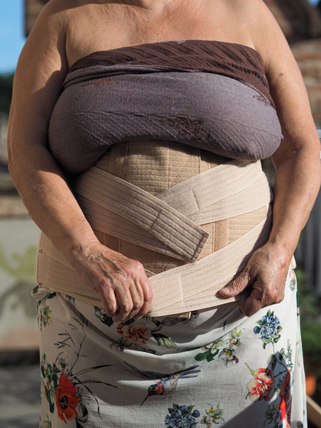 A shallow focus of a lady wearing a semi-rigid thoracic lumbosacral corset for curing lumbalgia - Fotó, kép