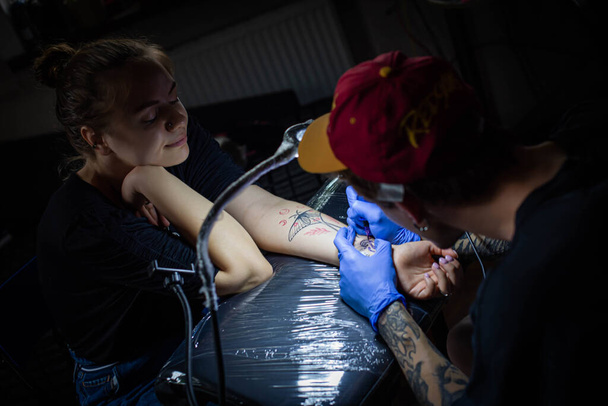 recortado tiro de proceso de tatuaje en la mano en el salón. Un artista profesional del tatuaje introduce tinta en la piel usando una aguja de una máquina de tatuaje.Tatuaje profesional que trabaja en el estudio. - Foto, Imagen
