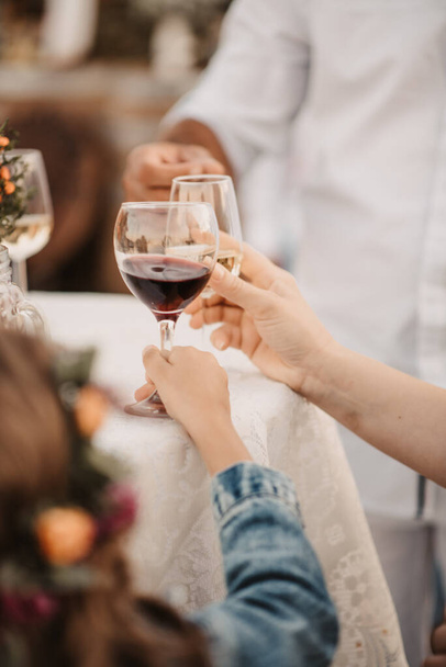 People cheering each other with a glass of red wine at a celebration - Photo, Image