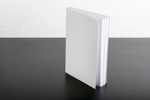 A book with a blank cover put on a black table - editable mockup template - Foto, imagen