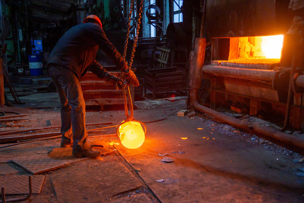 kovárna tovární dělník pohybující zářící horké kovové obrobky s řetězovým jeřábem focreps - Fotografie, Obrázek