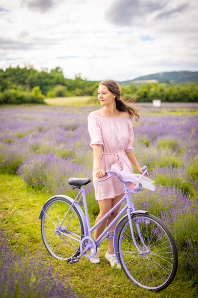 Woman in pink dress with retro bicycle in lavender field, Czech republic - Fotó, kép