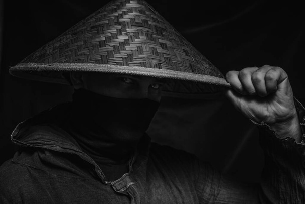 Ninja in hat posing over dark background - Φωτογραφία, εικόνα