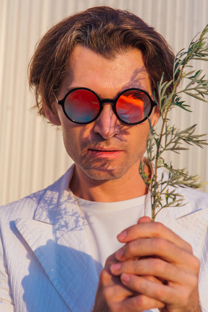 Close up portrait of a handsome man with round hippie sunglasses during sunset - Photo, image