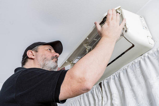 Professional air conditioning technician checking the cover of an internal unit of a split air unit. - Photo, Image