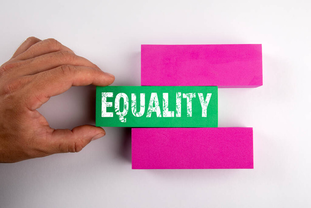 Равенство. Цветные блоки и руки мужчин на белом фоне - Фото, изображение