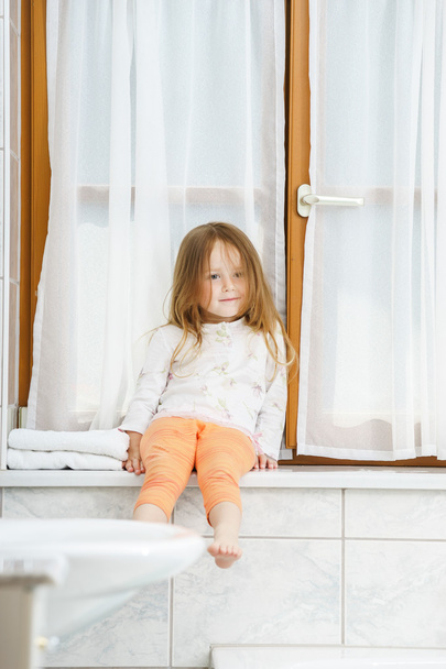 Cute little girl sitting on a bathroom window - Photo, Image