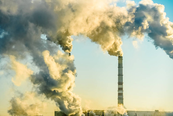 Rauchende Fabrikschornsteine. Umweltproblem der Umwelt- und Luftverschmutzung in Großstädten. Klimawandel, Ökologie und globale Erwärmung. Der Himmel ist verraucht mit giftigen Substanzen. Ruß aus Fabriken - Foto, Bild