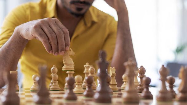 Чоловік грає в шахи вдома, він переміщує фігуру на шахівниці, концепція стратегічних ігор
 - Фото, зображення