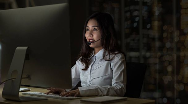 Азійська жінка підтримує стіл важко працювати в кінці нічної зміни в офісі, кол-центрі і концепції обслуговування клієнтів - Фото, зображення