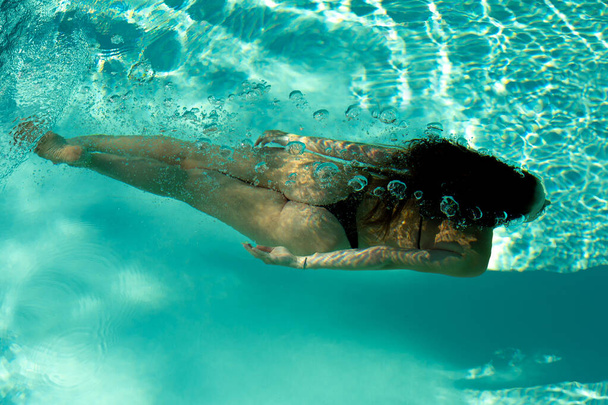 Woman swimming underwater in a blue pool - Foto, imagen
