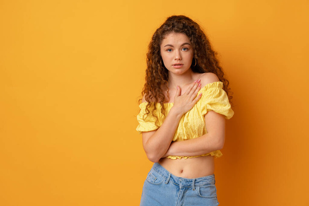 Portrait of a young curly-haired woman against yellow background - Фото, изображение