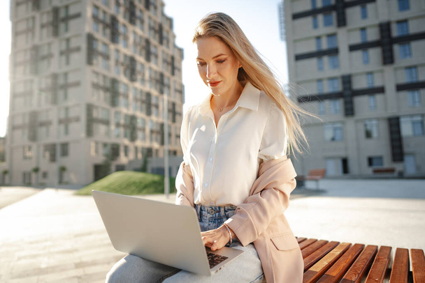 Young successful businesswoman using laptop for work outdoors - Valokuva, kuva
