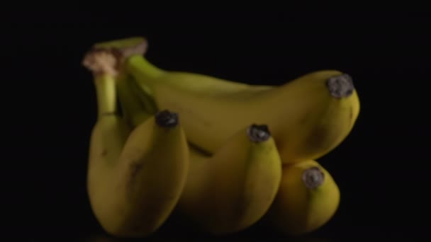 Close-up shot van verse roterende bananen met een zwarte achtergrond. - Video