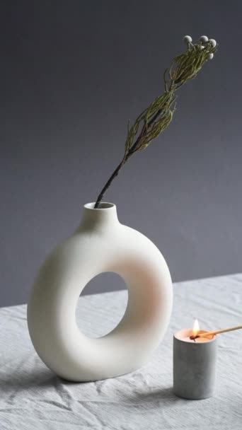 Verticale no people shot di composizione minimalista contemporanea con candela accesa e fiore in vaso sullo sfondo grigio - Filmati, video