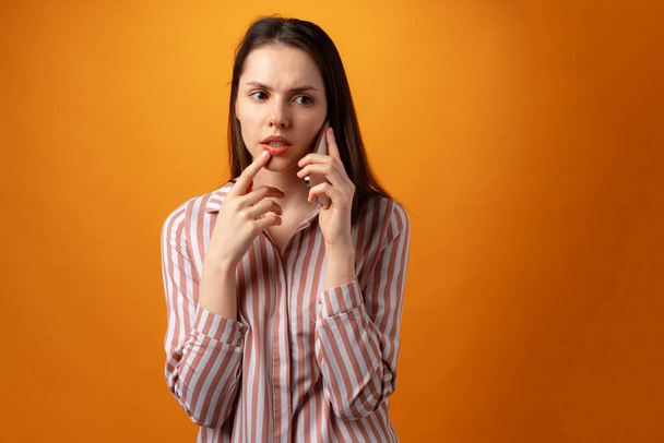 Mujer joven frustrada estresada sosteniendo teléfono inteligente, recibió malas noticias, fondo amarillo - Foto, Imagen