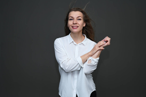 Portrait of a caucasian girl with a smile posing in a white shirt on a gray background - Valokuva, kuva