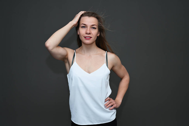 Portrait of a caucasian girl posing in a white blouse on a gray background - Fotó, kép