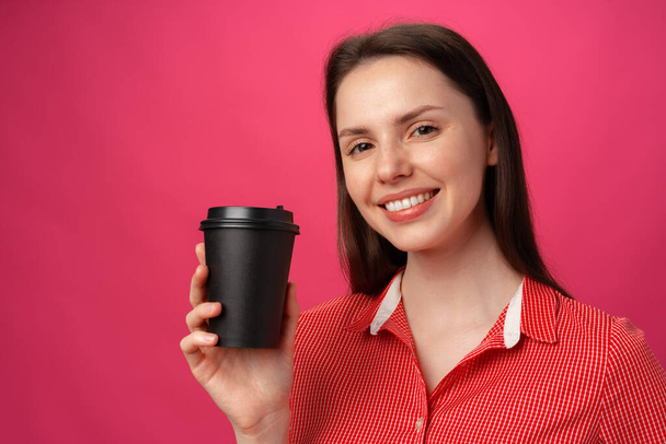 Portrait of attractive young woman with coffee cup against pink background - Fotó, kép