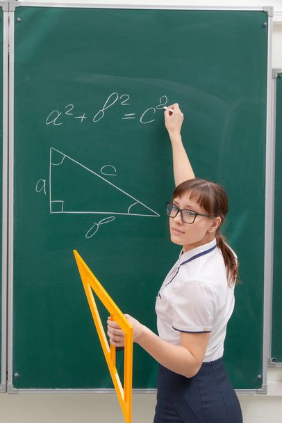 školní učitelka mladá žena ve třídě na tabuli kreslí trojúhelník s pravítkem. portrét. zavřít - Fotografie, Obrázek