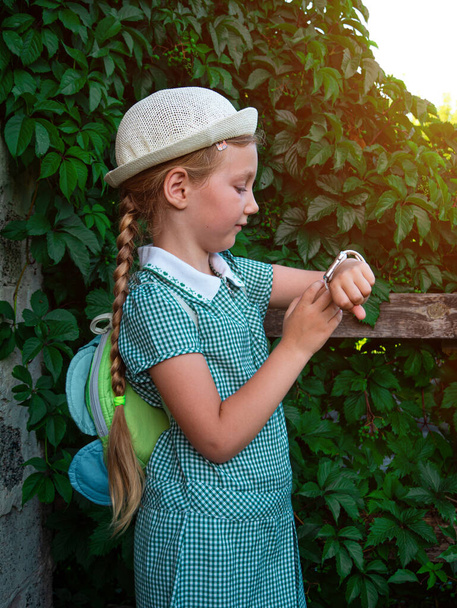 Schulkind benutzt Smartwatch Outdoor Park. Kid talking on vdeo call mit Eltern auf Smartwatches. Schulmädchen sucht im Internet mit Uhren Touchscreen-Display.Smart Armbanduhr GPS-Tracker - Foto, Bild