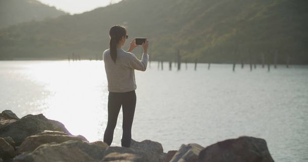 Žena fotit při západu slunce na moři - Fotografie, Obrázek