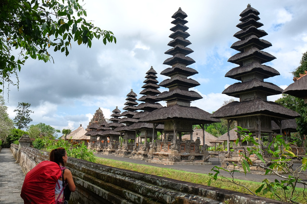 旅行バックパックを持つ若い白人女性の観光客は、 Mengwi寺でタマンAyunを訪問します。インドネシアのバリ - 写真・画像