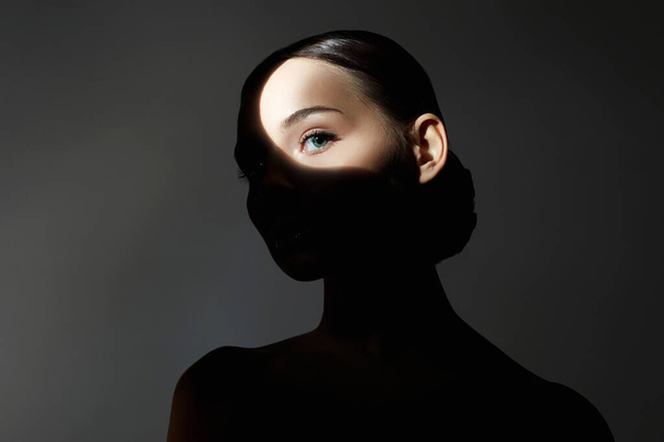 beautiful girl in the dark. portrait of young woman with light on her face - 写真・画像