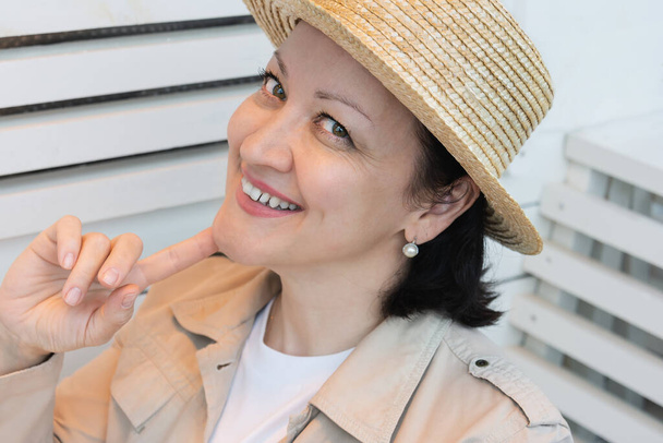 Portrét usměvavé mladé ženy v letních šatech a slaměný klobouk sedící na letní terase kavárny. - Fotografie, Obrázek