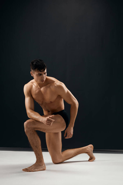 man with a pumped-up body in dark panties Studio model - Foto, imagen