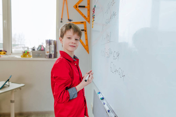 教室でフェルトチップで黒板に書く小学生の姿 - 写真・画像