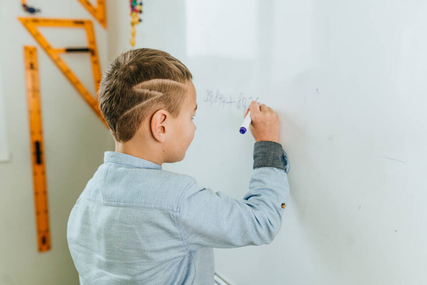Студент початкової школи, який пише на дошці за фетром у класі
 - Фото, зображення