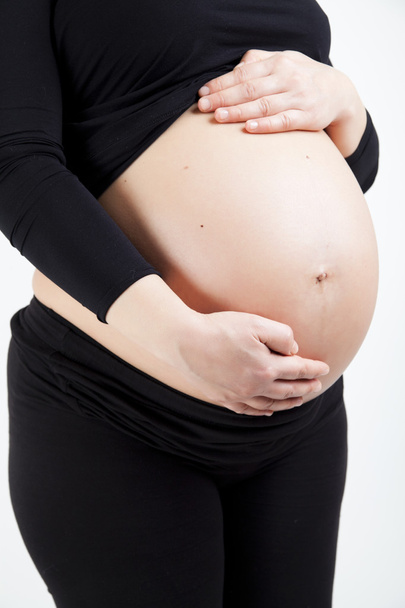 Schwangere berührt ihren Bauch mit Händen - Foto, Bild