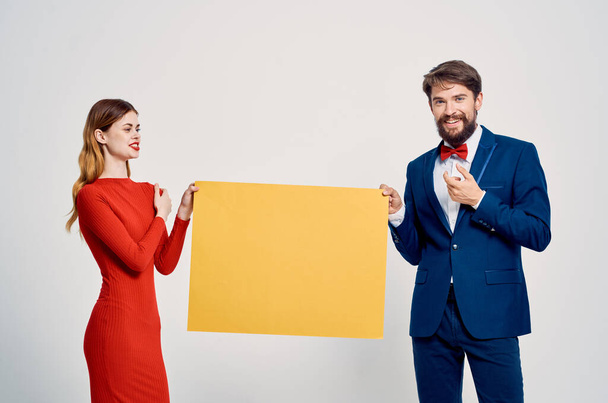 мужчина и женщина за рекламным плакатом желтого мокапа - Фото, изображение
