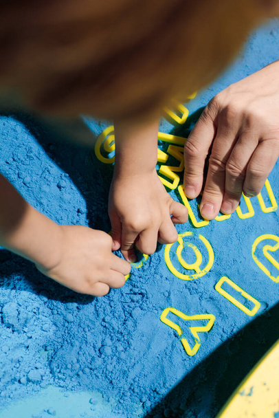 Word JOY, laid out in kinetic sand by children's hands. Art therapy. Relieving stress and tension. Tactile sensations. Learning through the game. Development of fine motor skills. Concentration . - Fotografie, Obrázek