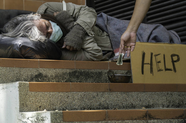 Obdachlosen am Straßenrand Geld geben. - Foto, Bild