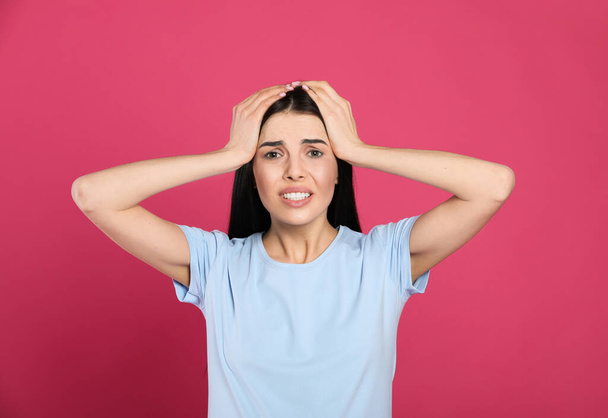 Woman suffering from migraine on pink background - Foto, afbeelding