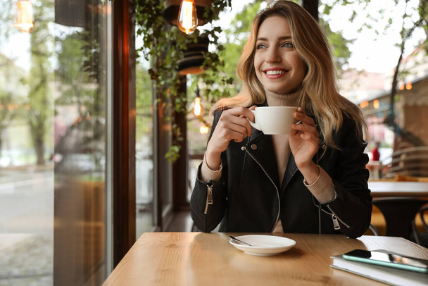 Sabahları kafede kahve içen genç bir kadın. - Fotoğraf, Görsel